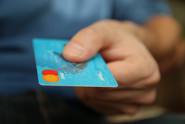 person-holding-out-their-debit-card person-holding-out-their-debit-card