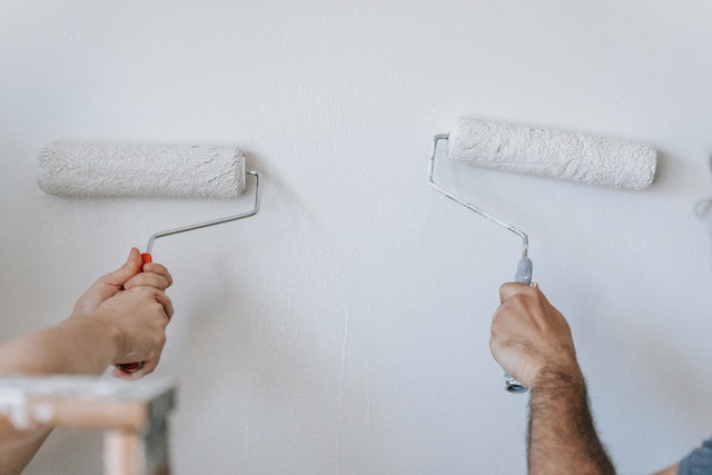 two-people-paint-a-wall-with-paint-rollers two-people-paint-a-wall-with-paint-rollers